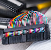 Colored multi wire connector. Ribbon cables detail in blurred background. Internal drive electronics of data storage devices as floppy, compact or hard disks. Spare computer hardware. Selective focus.